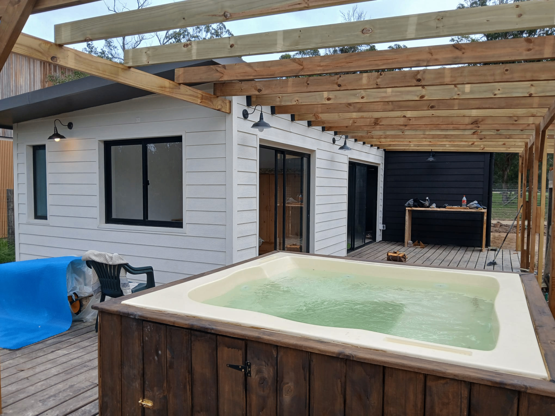 Deck exterior con jacuzzi y pérgola de madera